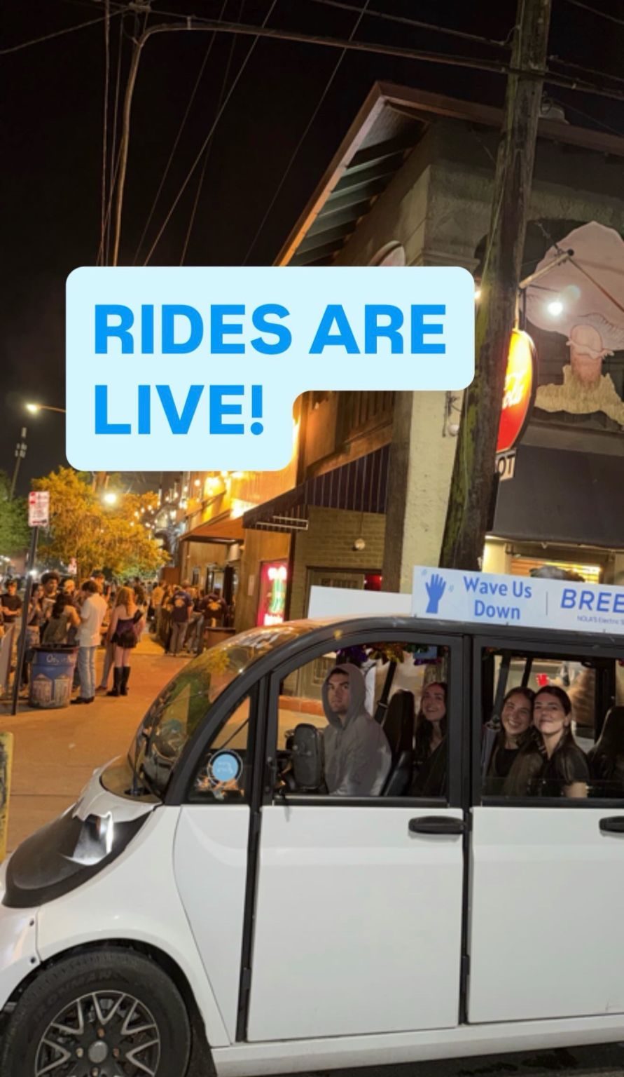 Breeze shuttle on a night street with a Wave Us Down roof sign